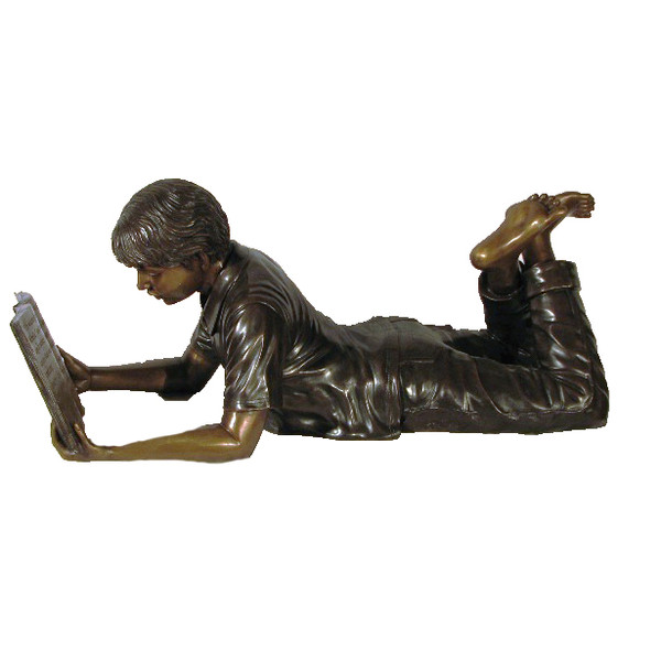 Life size bronze statue of boy reading a book while on his stomach